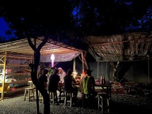 eine Gruppe von Menschen, die an einem Tisch in einem Zelt sitzen in der Unterkunft Himmapun Farmstay in Ban Pa Ngiu