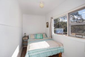 une petite chambre avec un lit et une fenêtre dans l'établissement Retro Beach Cottage - classic surf getaway, à Kioloa 11 autres photos