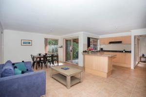 Una sala de estar con un sofá azul y una mesa. en Leafy Retreat - spacious holiday home near harbour, en Ulladulla