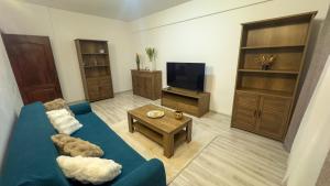 a living room with a blue couch and a tv at Sweet Inn Apartment in Piteşti