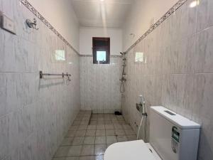 a bathroom with a toilet and a tiled wall at Upton Estate Homestay in Deniyaya