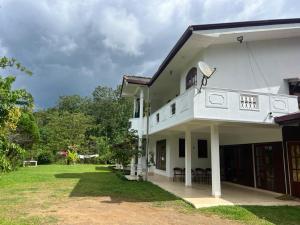 a white house with a lawn in front of it at Upton Estate Homestay in Deniyaya