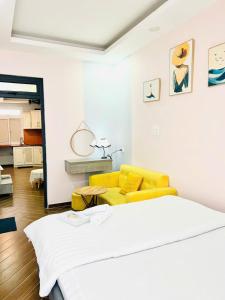 ein Schlafzimmer mit einem weißen Bett und einer gelben Couch in der Unterkunft LALA HOUSE - CĂN HỘ Đà Lạt in Khu Chi Lăng