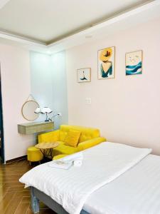 ein Schlafzimmer mit einem Bett und einer gelben Couch in der Unterkunft LALA HOUSE - CĂN HỘ Đà Lạt in Khu Chi Lăng