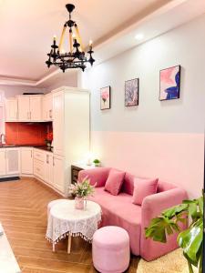 ein Wohnzimmer mit einem rosa Sofa und einem Tisch in der Unterkunft LALA HOUSE - CĂN HỘ Đà Lạt in Khu Chi Lăng