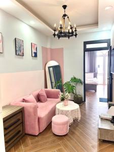 ein Wohnzimmer mit einem rosa Sofa und einem Tisch in der Unterkunft LALA HOUSE - CĂN HỘ Đà Lạt in Khu Chi Lăng