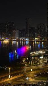 miasto w nocy z fontanną w wodzie w obiekcie Bed space in al majaz 2 w Szardży