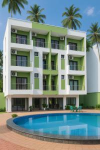 ein Apartmentgebäude mit einem Pool und Palmen in der Unterkunft Hotel Shiva Classic, Calangute Beach Goa in Calangute