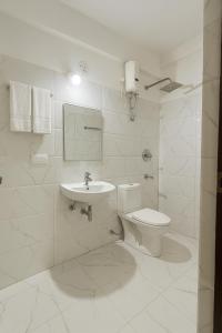 ein weißes Badezimmer mit Toilette und Waschbecken in der Unterkunft Hotel Shiva Classic, Calangute Beach Goa in Calangute