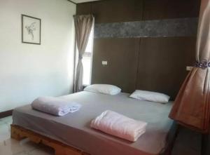a bed with two pillows on it in a room at We Home Guesthouse in Ban Pa Bong