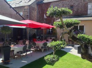 a patio with tables and chairs and red umbrellas at Hôtel La Gibecière in Lohéac