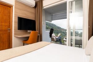 Eine Frau, die auf einem Stuhl sitzt und ein Buch in einem Schlafzimmer liest. in der Unterkunft MYSA Sky Suites, Lakkidi in Vythiri