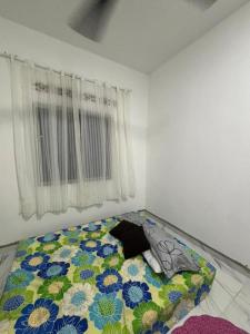 een slaapkamer met een bed met een bloemenpatroon bij Nora Guest House in Kerteh