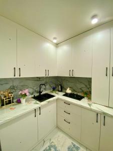 a white kitchen with white cabinets and a sink at Appartament Shymkent in Shymkent +7 photos
