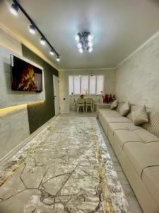 a living room with a couch and a tv on a wall at Appartament Shymkent in Shymkent