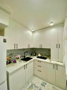 a white kitchen with white cabinets and a sink at Appartament Shymkent in Shymkent