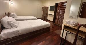 una habitación de hotel con dos camas y un televisor en Prince Hotel Chiang Mai, en Chiang Mai