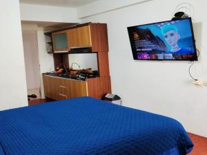a bedroom with a blue bed and a flat screen tv at Antareja Urban Town By Reccoma in Dukuh