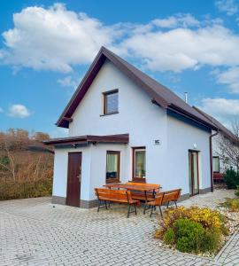 a white house with a picnic table and two benches at Enklawa Pana Pszczoły in Szczytna