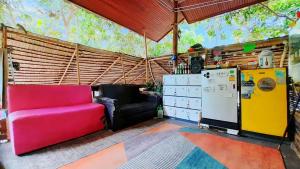 a living room with a red couch and a refrigerator at Neena S House in Koh Phangan