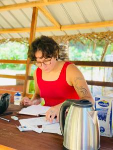 a woman sitting at a table writing in a book at Mermaid Hostel in Trincomalee +38 photos