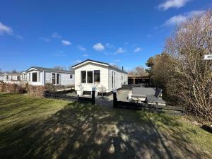 a white house with a patio and a yard at Chalet 218 in Petten