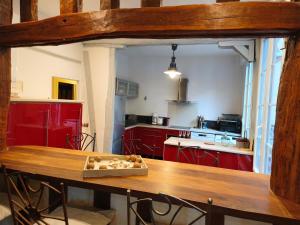 a kitchen with red cabinets and a wooden table at Le Vieux Palais Hypercentre Rouen, Place Vieux Marché - Linge & Ménage Inclus in Rouen +9 photos