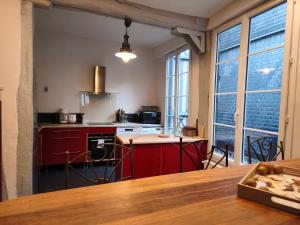 a kitchen with red cabinets and a large window at Le Vieux Palais Hypercentre Rouen, Place Vieux Marché - Linge & Ménage Inclus in Rouen