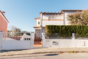 ein weißes Haus mit einem weißen Zaun in der Unterkunft Surf Lodge Santa Cruz in Silveira