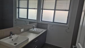 a bathroom with two sinks and two windows at Silverwood 17th Hole Retreat in Yarrawonga +5 photos