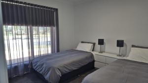 a bedroom with two beds and a large window at Silverwood 17th Hole Retreat in Yarrawonga