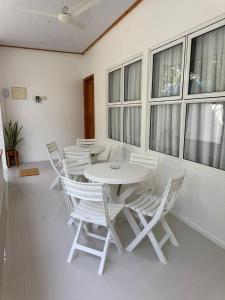 ein weißer Tisch und Stühle in einem Raum mit Fenstern in der Unterkunft The Palm Retreat Maldives in Gaafaru