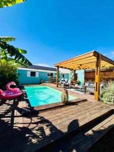 a wooden deck with a swimming pool and a pavilion at La case d'Édith in Le Tampon
