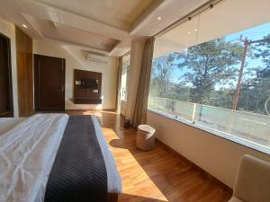 Un dormitorio con una cama y una ventana grande. en Castle INN Hotel, en Rājpur