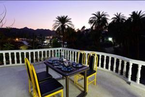 a table and chairs on a balcony with a view at The Boho Peach Villa in Mount Ābu