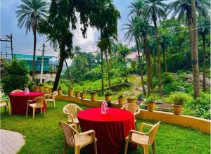 Un restaurante con mesas y sillas rojas y palmeras. en The Boho Peach Villa, en Mount Abu