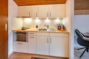 a kitchen with white cabinets and a sink at Studio PEAK fantastic view in Zermatt +14 photos