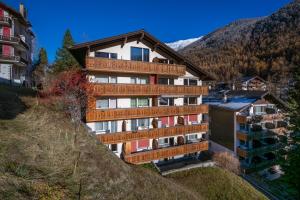 a building on a hill with mountains in the background at Studio PEAK fantastic view in Zermatt