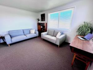 a living room with two couches and a piano at Top of Tyne - Peace, Comfort & Local Connection in Oamaru