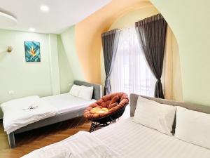 a room with two beds and a chair and a window at Lá Home - Căn Hộ Đà Lạt in Khu Chi Lăng