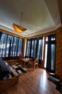 Una sala de estar con mesa y sillas y ventanas. en Oreos cafe and stay shangarh, en Shangarh