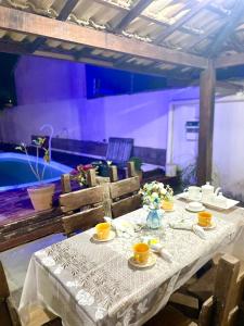 a table with a white table cloth and cups and a tub at Aconchegante casa de Temporada em Búzios. in Armacao dos Buzios