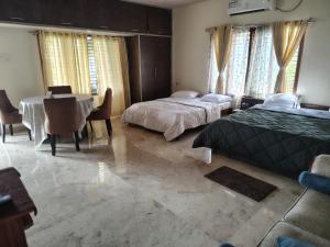 迈索尔Blue Moon Homestay的一间带两张床和一张桌子的卧室和一间餐厅 更多3张照片