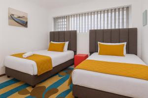 two beds sitting next to each other in a room at 606 L'esclaier Cabanas - Seaside Paradise in Amanzimtoti +12 photos