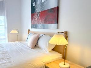 a bed with two lamps and a painting on the wall at Beachcomber Motel & Apartments Apollo Bay in Apollo Bay