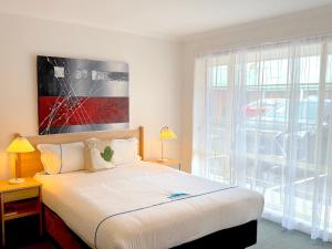 a bedroom with a bed and a large window at Beachcomber Motel & Apartments in Apollo Bay
