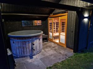 an outside shower with a wooden barrel next to a building at Buitenplaats Appelhoeve met sauna en hottub in Appelscha