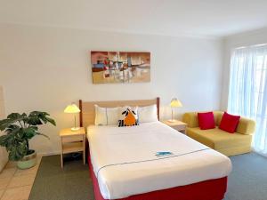 Un dormitorio con una cama grande y un sofá. en Beachcomber Motel & Apartments, en Apollo Bay