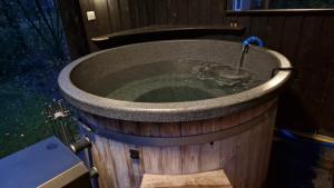 a large wooden bath tub with a water fountain at Buitenplaats Appelhoeve met sauna en hottub in Appelscha