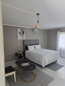 a bedroom with a large bed and a table at Ella Guest House in Pretoria